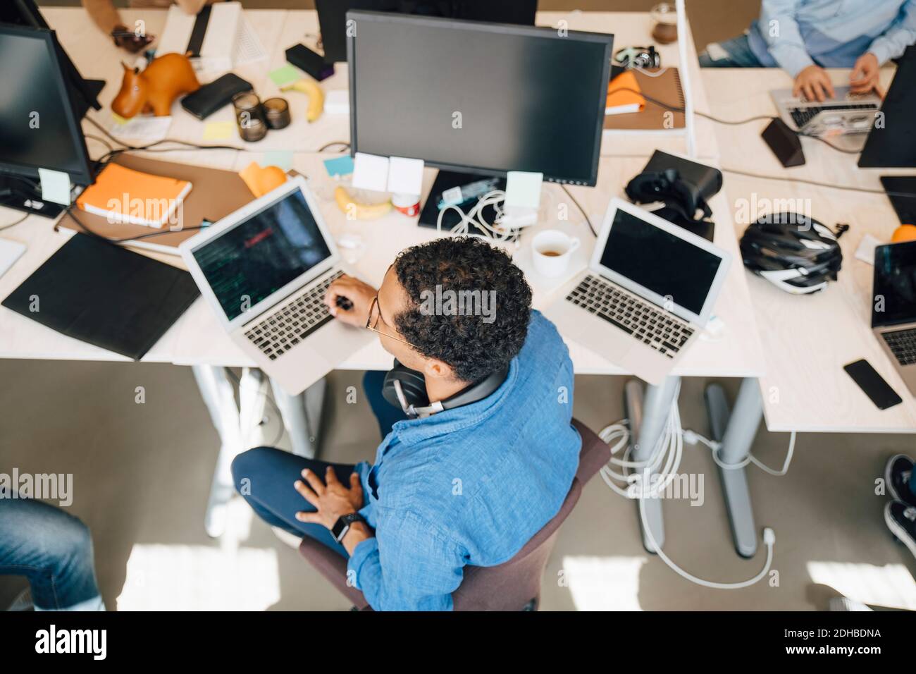 Vue en grand angle du pirate informatique avec un ordinateur portable assis bureau Banque D'Images