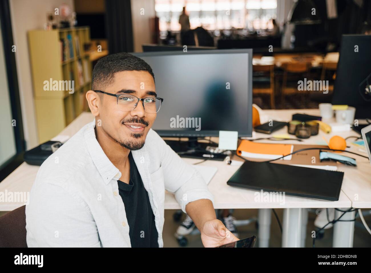 Portrait d'un pirate informatique confiant assis au bureau Banque D'Images