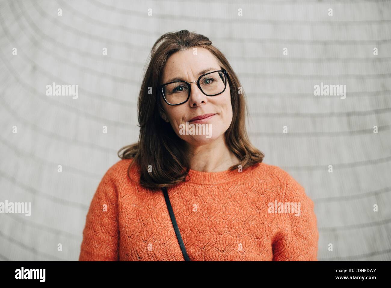 Portrait d'une femme d'affaires souriante contre un mur au bureau Banque D'Images