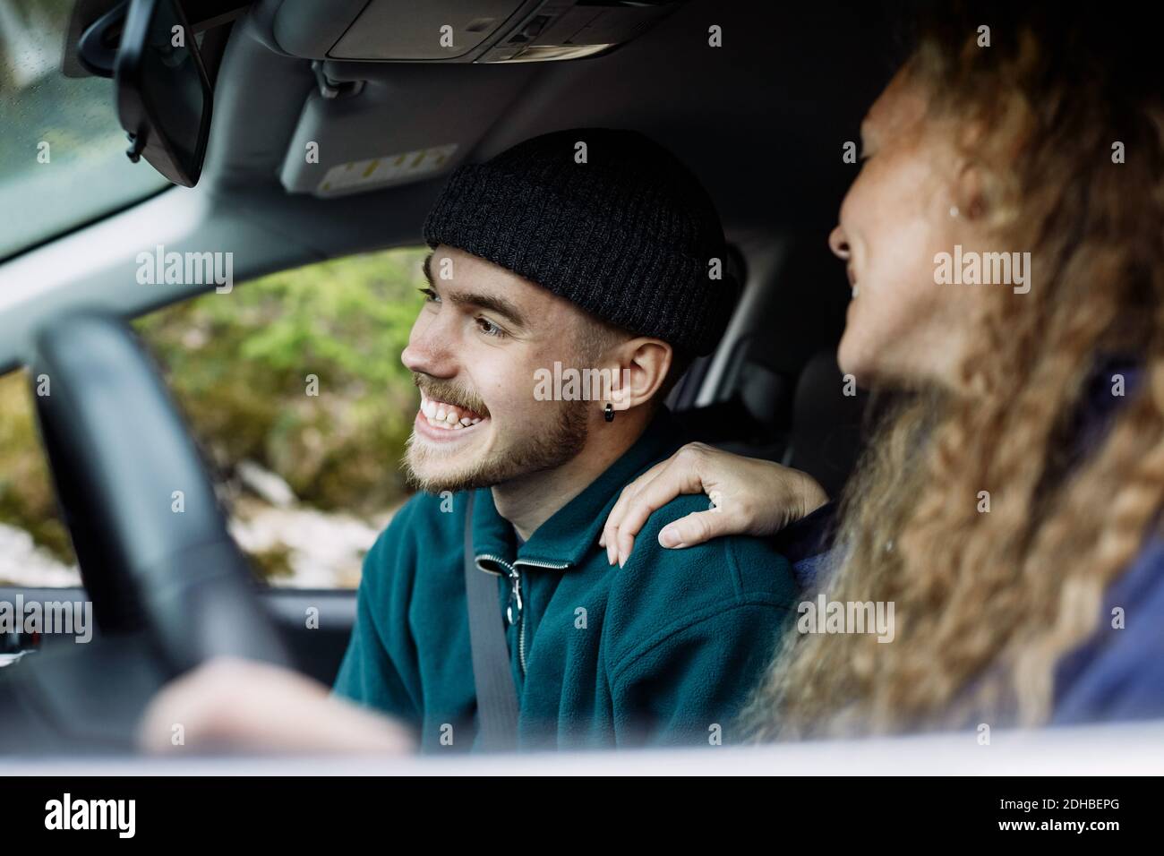 Jeune femme parlant avec un ami souriant en voiture Banque D'Images