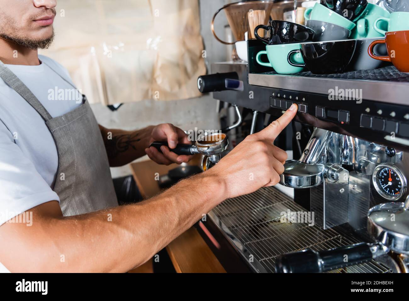 vue rognée du barista en appuyant sur le bouton de la machine à café pendant porte-filtre Banque D'Images