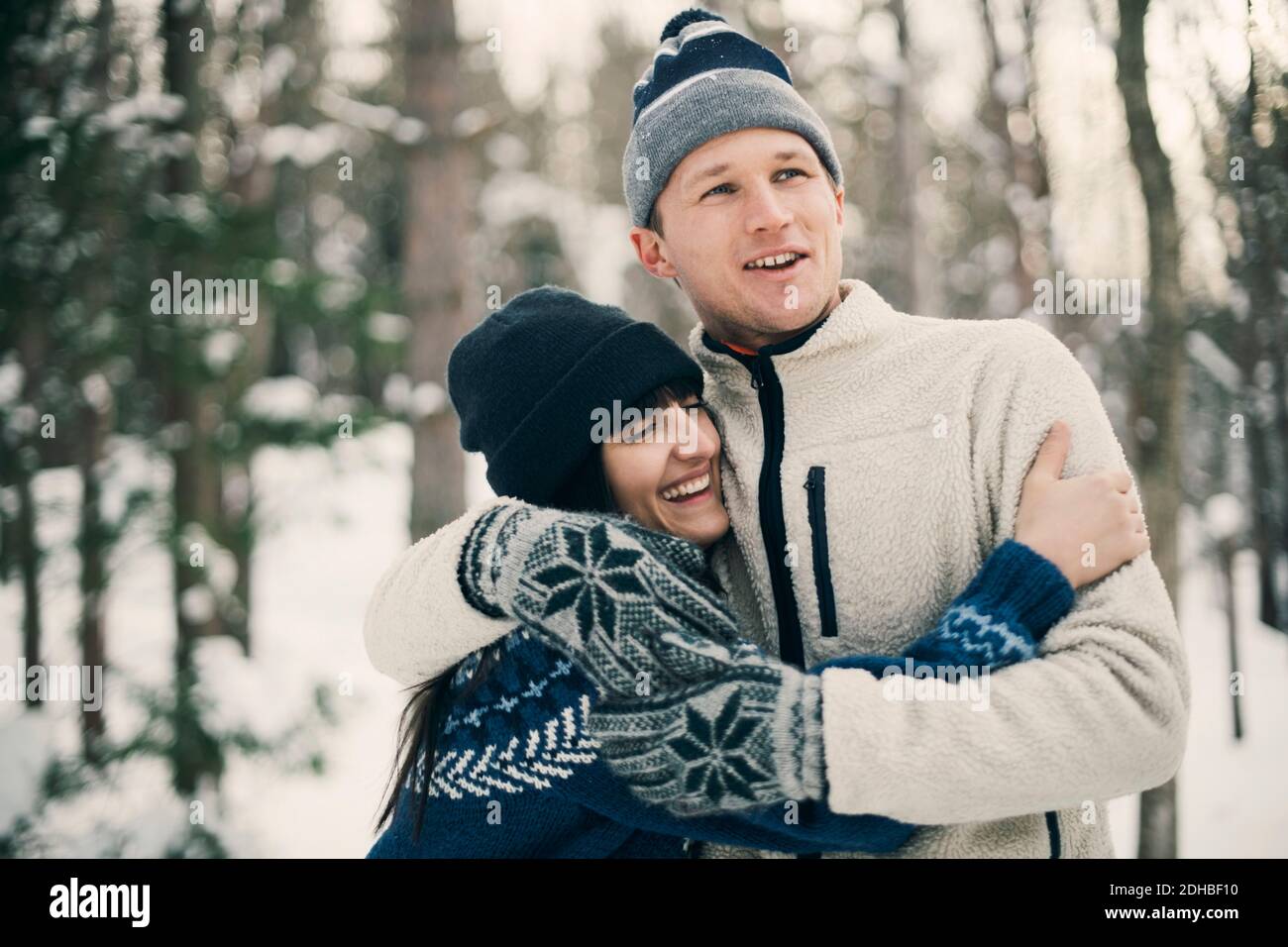 Des amis heureux s'embrassant en se tenant au parc pendant l'hiver Banque D'Images