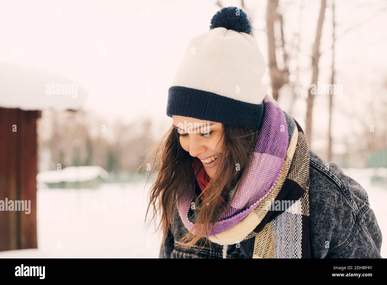 Femme de taille moyenne souriante qui regarde loin du parc couvert de neige Banque D'Images