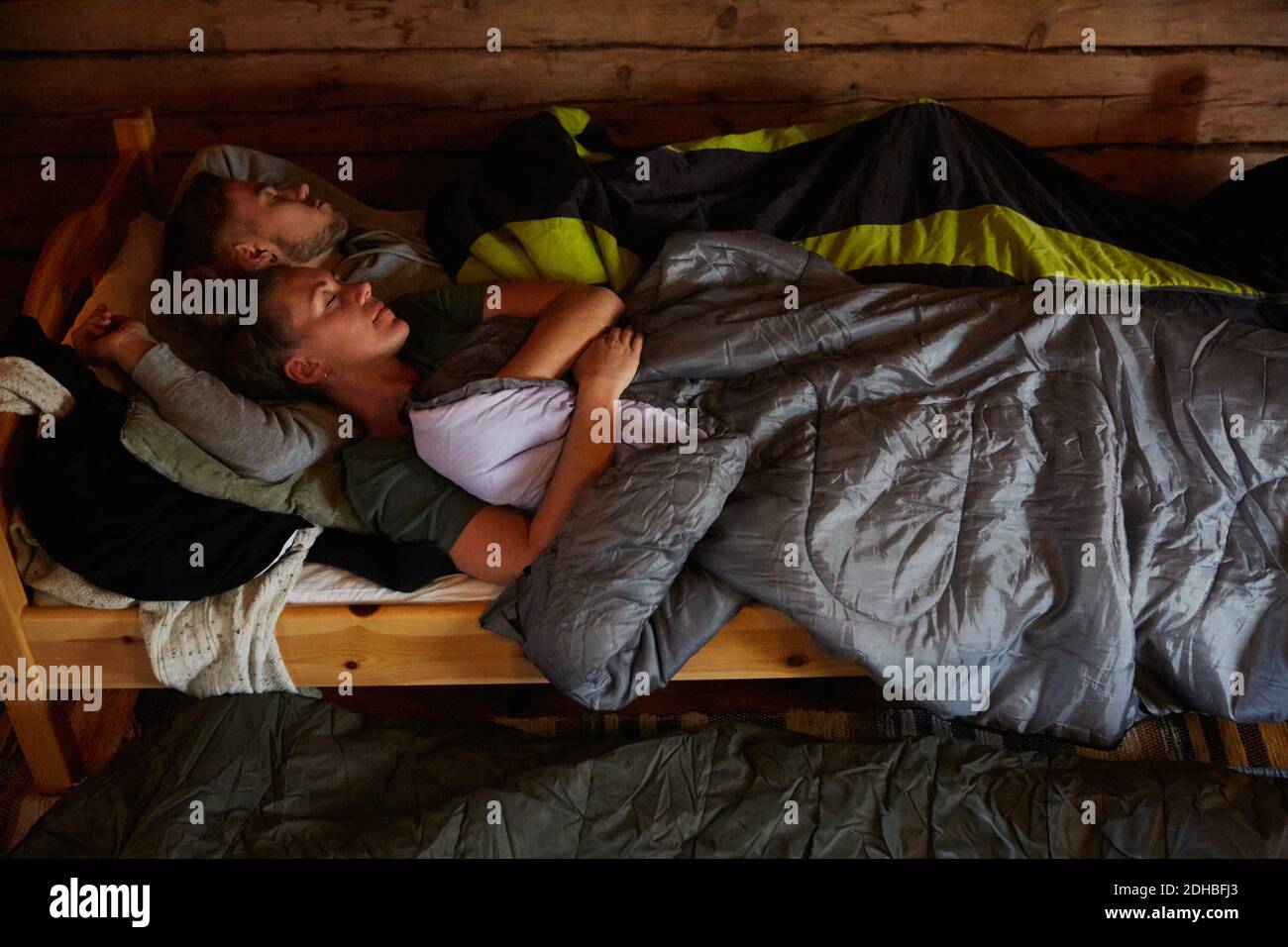 Vue en grand angle de couple avec couvertures dormant sur le lit dans la cabine en rondins Banque D'Images