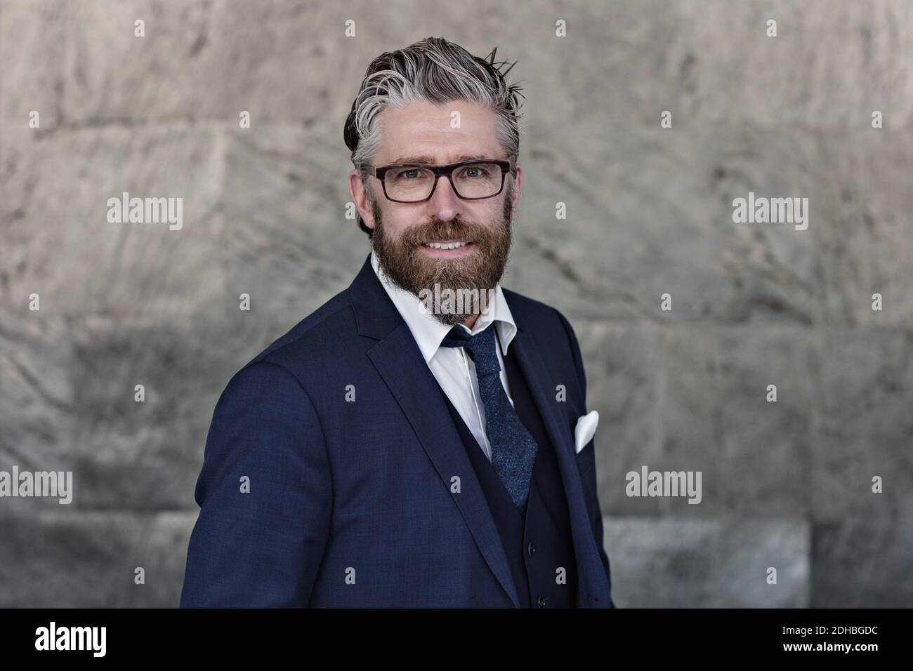 Portrait d'un homme d'affaires souriant en costume debout contre le mur Banque D'Images