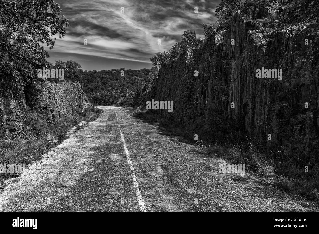 Une photo en niveaux de gris de la vieille route sur des montagnes rocheuses Banque D'Images