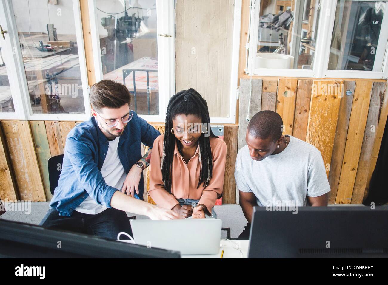 Vue en grand angle des jeunes pirates professionnels discutant sur ordinateur portable tout en encodant sur un lieu de travail créatif Banque D'Images