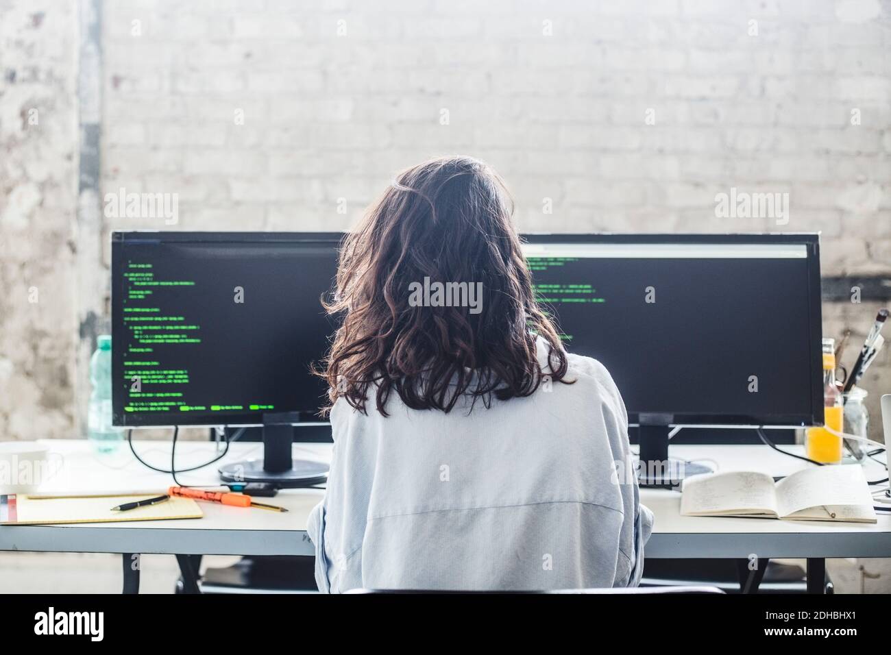 Vue arrière de l'ordinateur de hacker femelle codant au bureau dans bureau créatif Banque D'Images