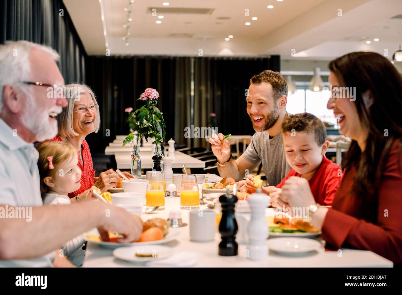 Une famille joyeuse qui parle tout en manant à table au restaurant Banque D'Images
