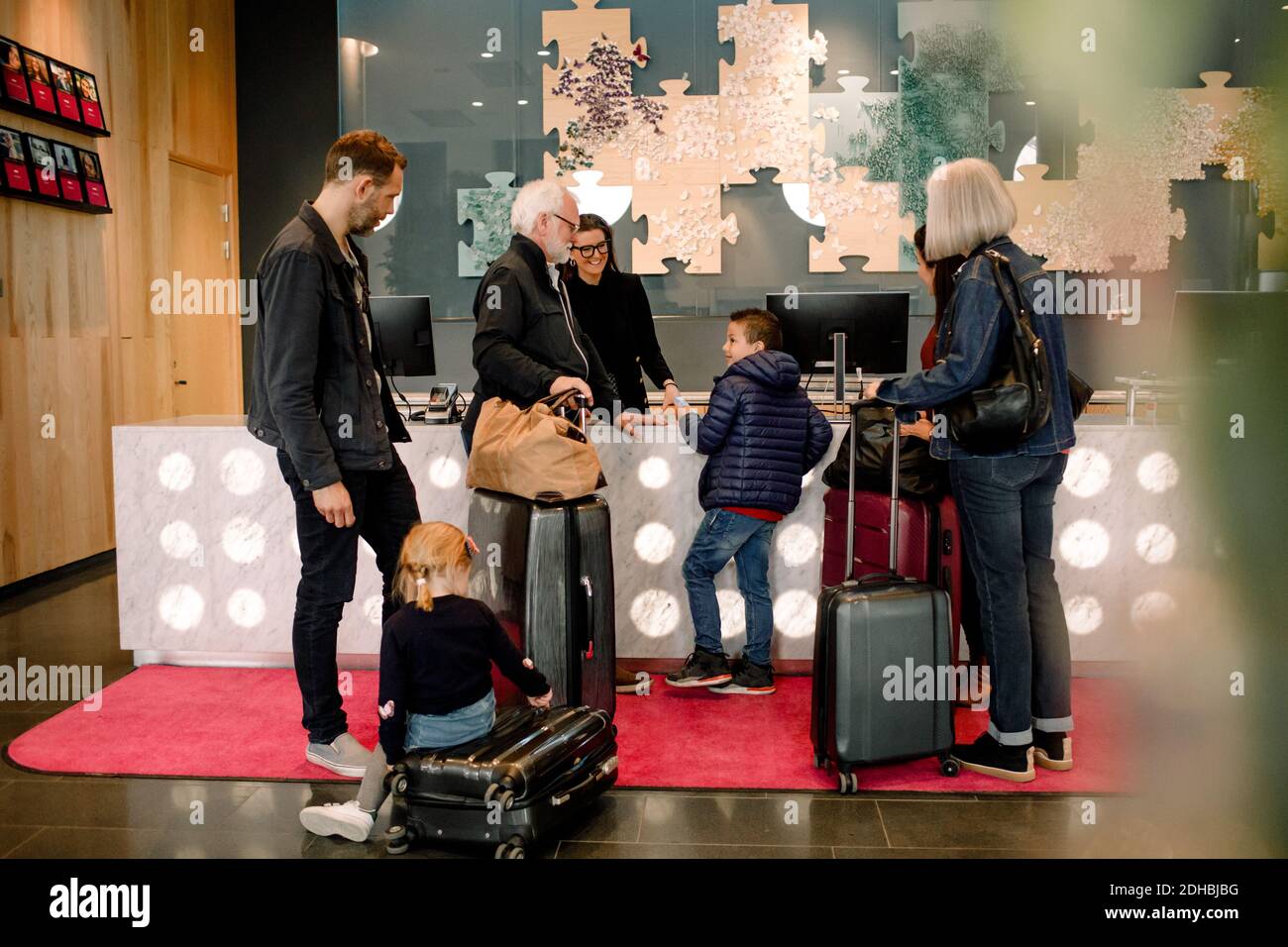 Réceptionniste souriant regardant un garçon debout avec une famille dans l'hôtel Banque D'Images