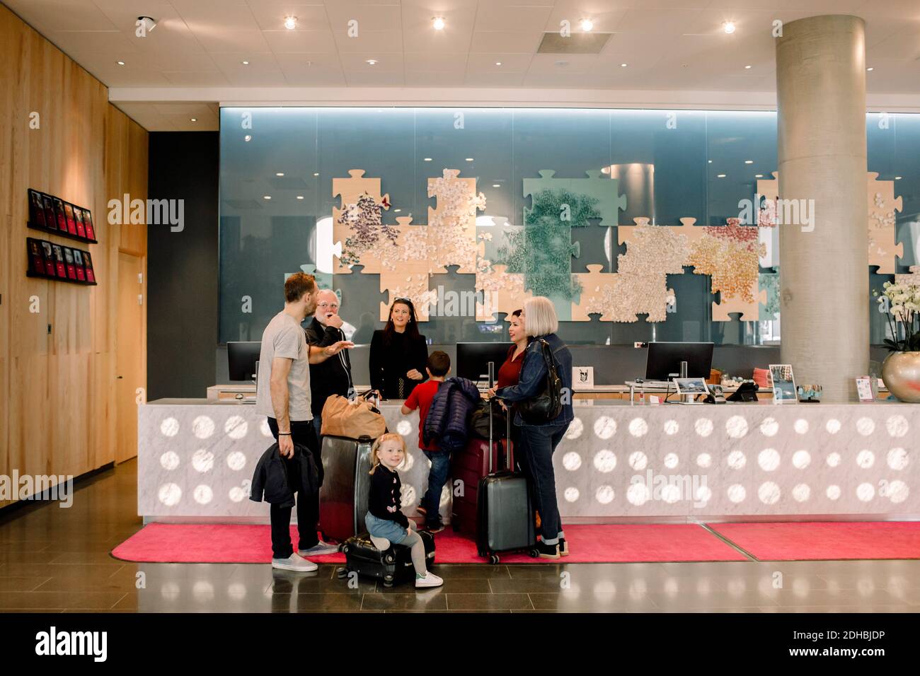 La famille regarde un homme qui parle à la réceptionniste de l'hôtel Banque D'Images
