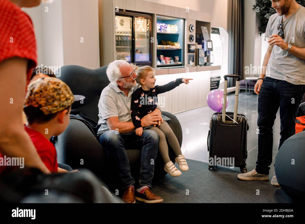 Fille souriante parlant à son père tout en étant assise avec son grand-père hall de l'hôtel Banque D'Images