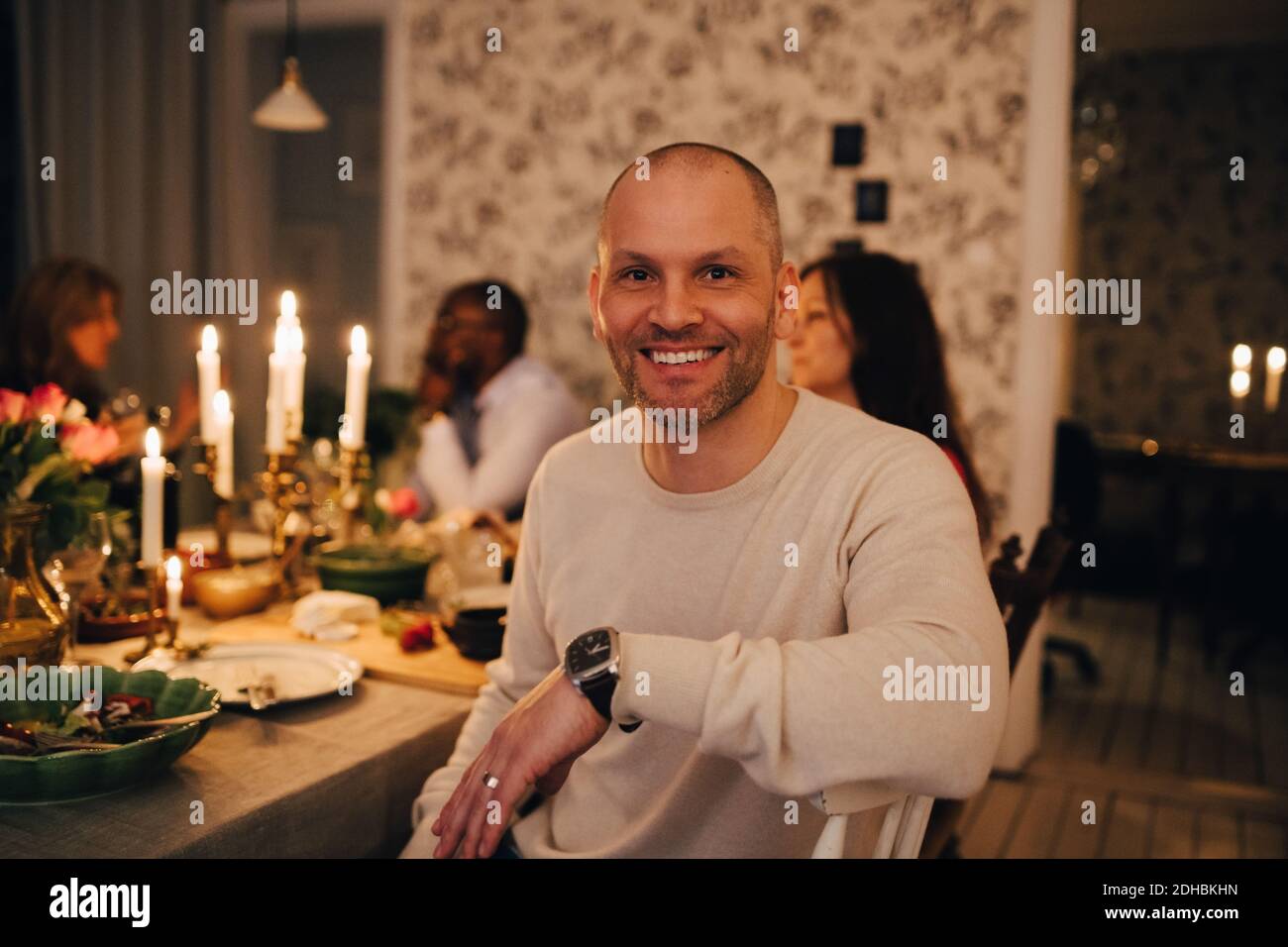 Portrait d'un homme mûr avec des amis à la table à manger dans dîner Banque D'Images