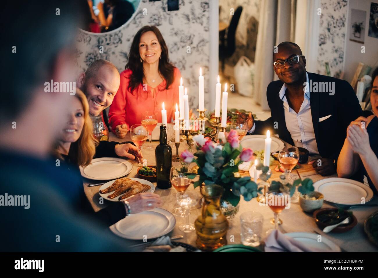 Vue en grand angle des amis matures souriants qui apprécient le dîner à la maison Banque D'Images