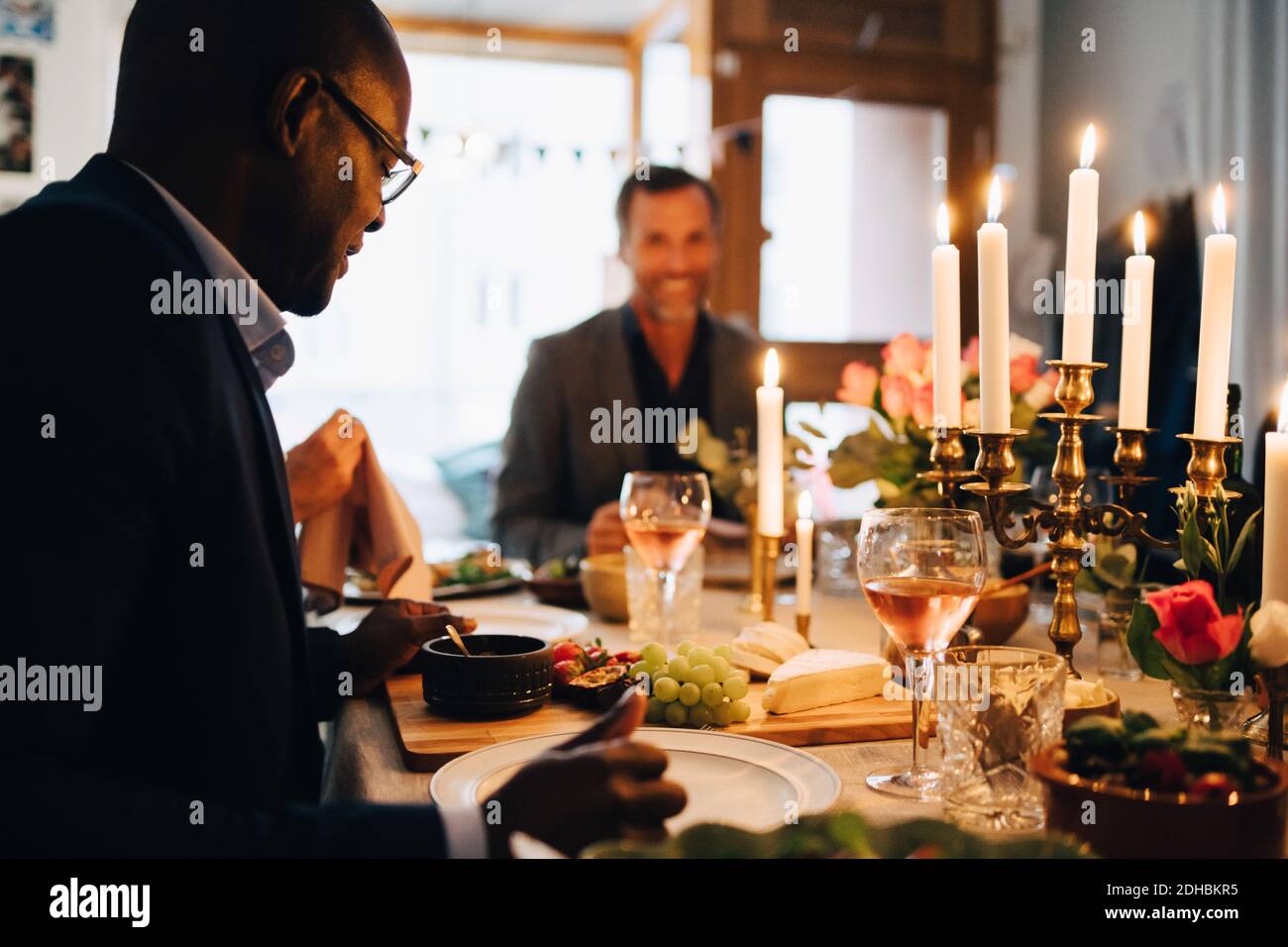 Homme mature qui dîne avec des amis à la table à manger dîner Banque D'Images