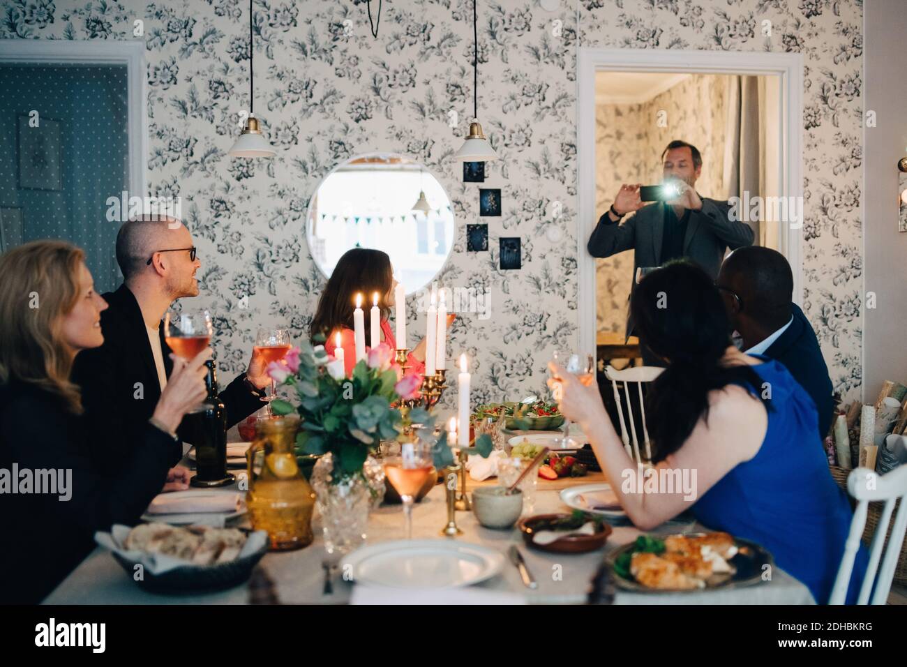 Homme photographiant des amis matures lors d'un dîner Banque D'Images