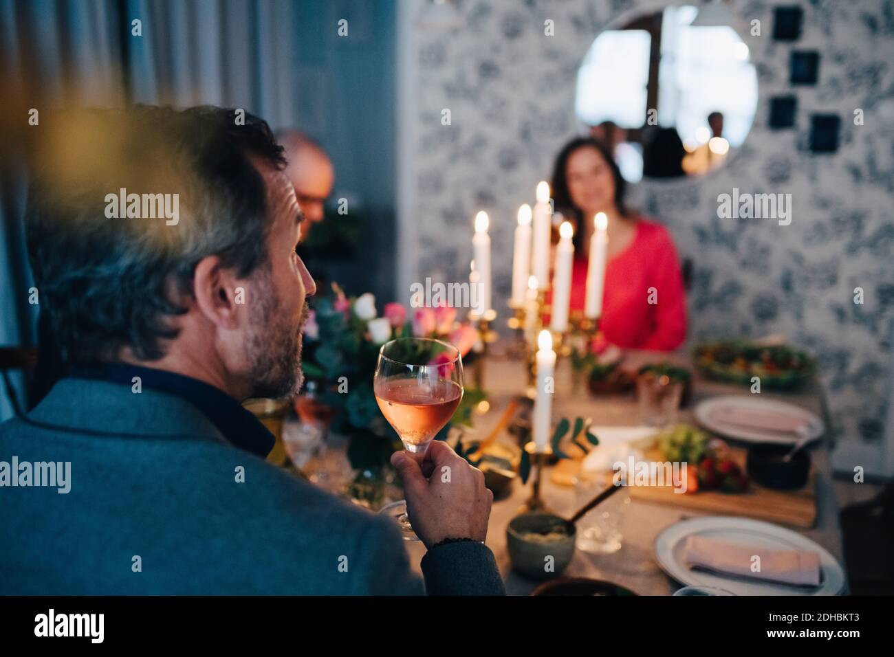 Homme mature ayant du vin tout en étant assis avec des amis au dîner fête Banque D'Images