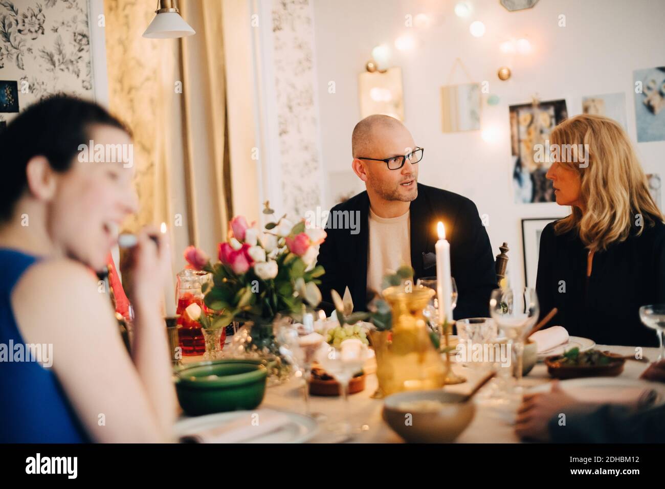 Des amis matures parlent tout en dégustant des plats lors d'un dîner-fête Banque D'Images