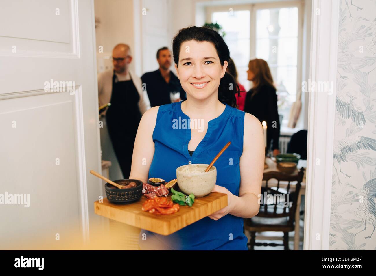 Portrait d'une femme souriante tenant un plateau de service debout porte en fête Banque D'Images