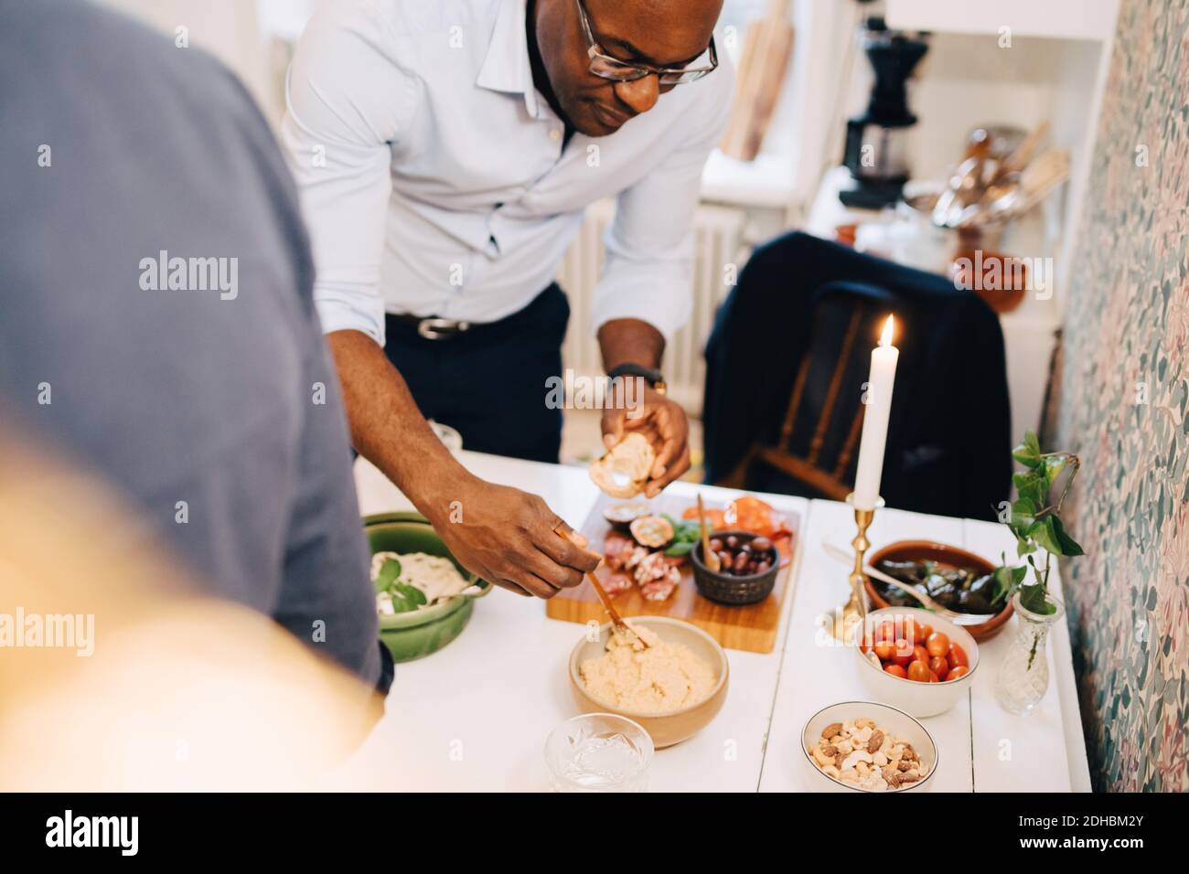 Homme mature ayant de la nourriture à la table de salle à manger en fête Banque D'Images