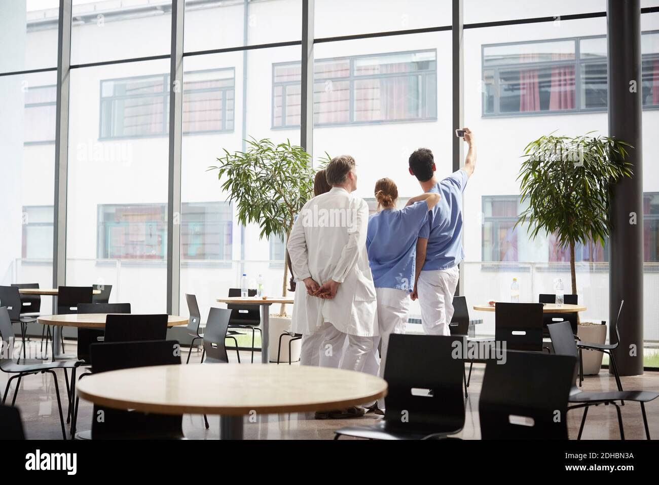 Vue arrière de l'infirmière qui prend le selfie avec l'équipe médicale à la cafétéria de l'hôpital Banque D'Images