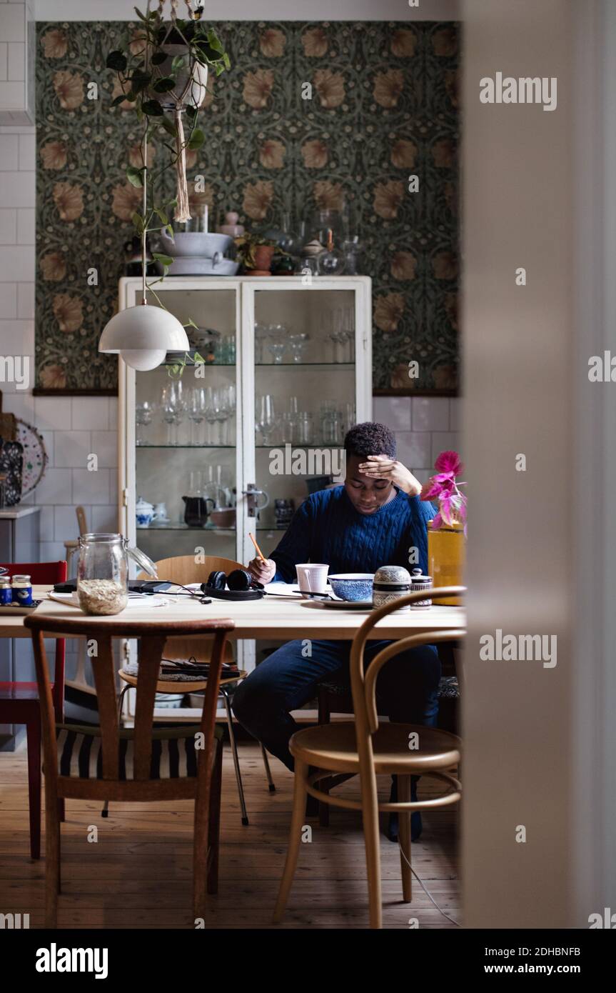 Adolescent avec la tête à la main étudiant à la maison Banque D'Images