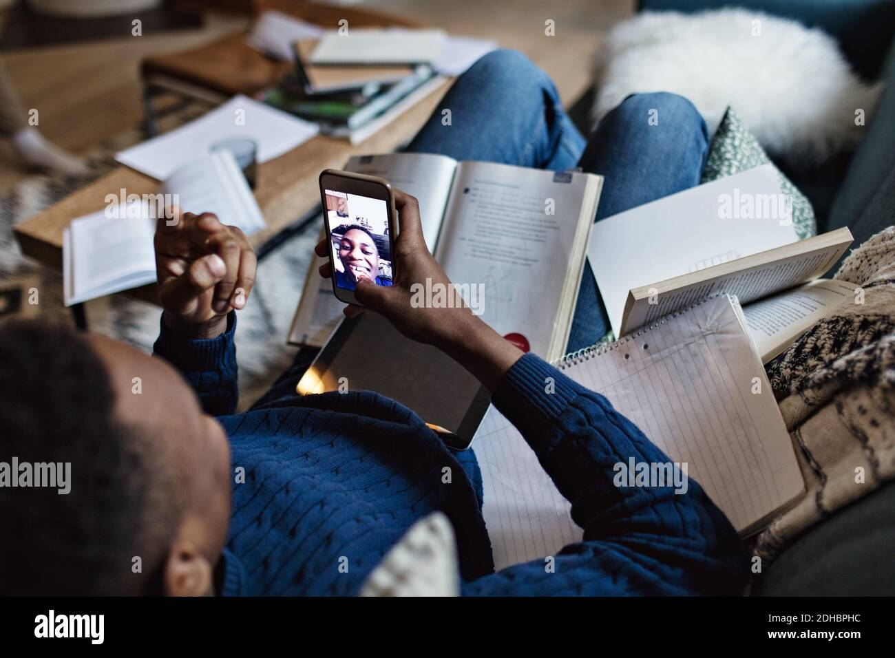 Vue en grand angle d'un adolescent heureux qui prend le selfie pendant étudier dans le salon à la maison Banque D'Images