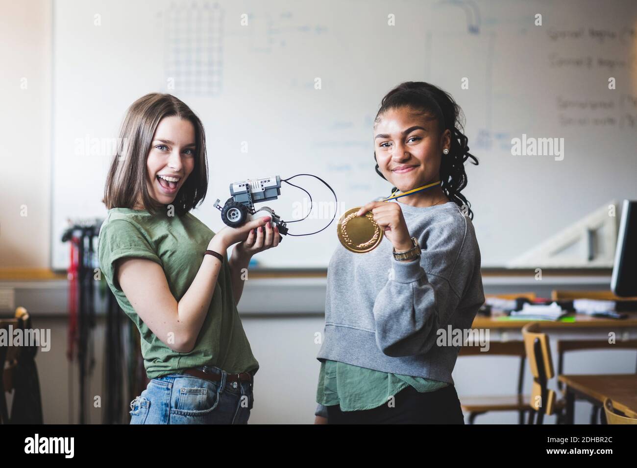 Portrait des adolescentes avec succès, portant un robot et de l'or médaille en classe à l'école secondaire Banque D'Images
