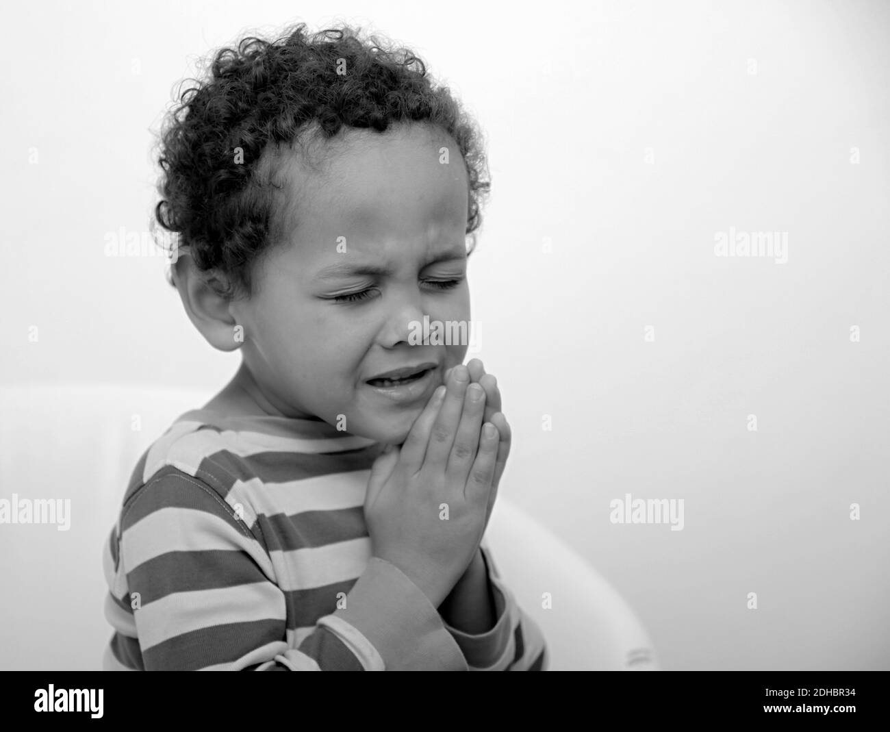 Garçon priant à Dieu avec les mains ensemble sur fond blanc photo Banque D'Images