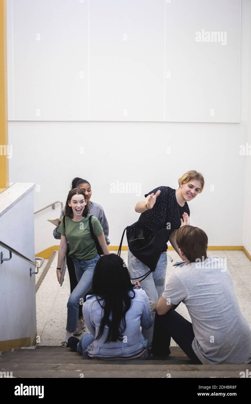 Vue en grand angle de l'accueil des étudiants multi-ethniques heureux sur les marches à l'école secondaire Banque D'Images