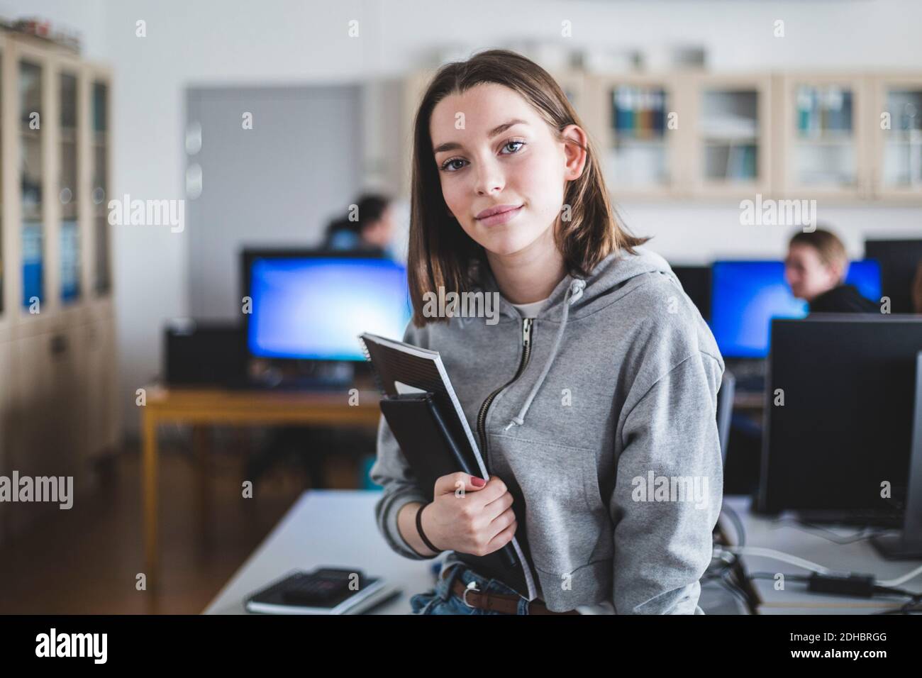 Portrait d'une étudiante de lycée confiante avec des livres salle de classe Banque D'Images
