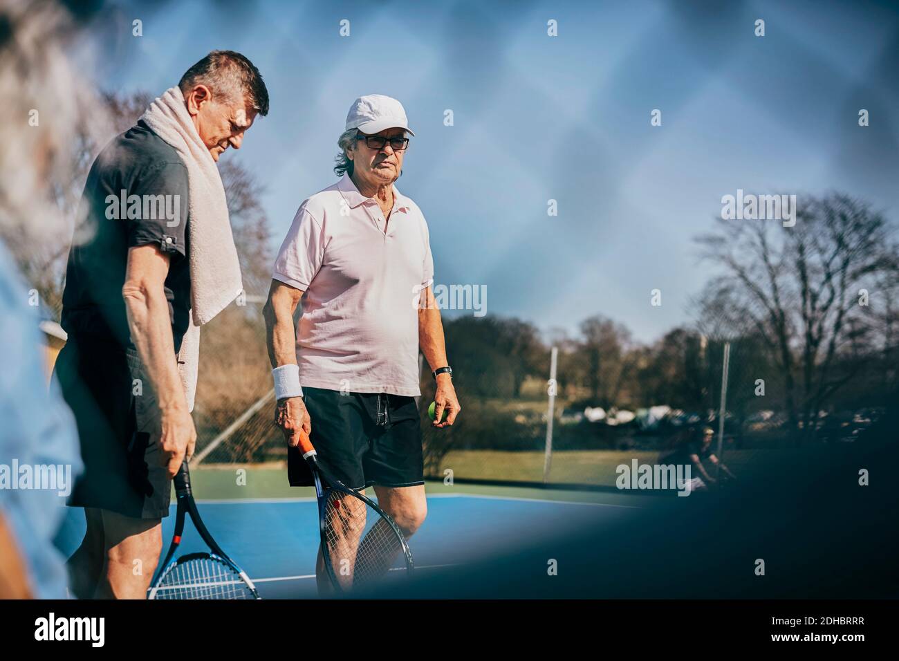 Des amis masculins confirmés avec des raquettes debout sur un court de tennis Banque D'Images
