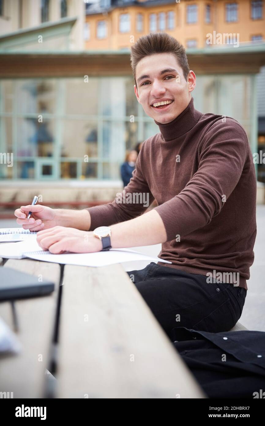 Portrait d'un adolescent souriant assis à table cour d'école Banque D'Images