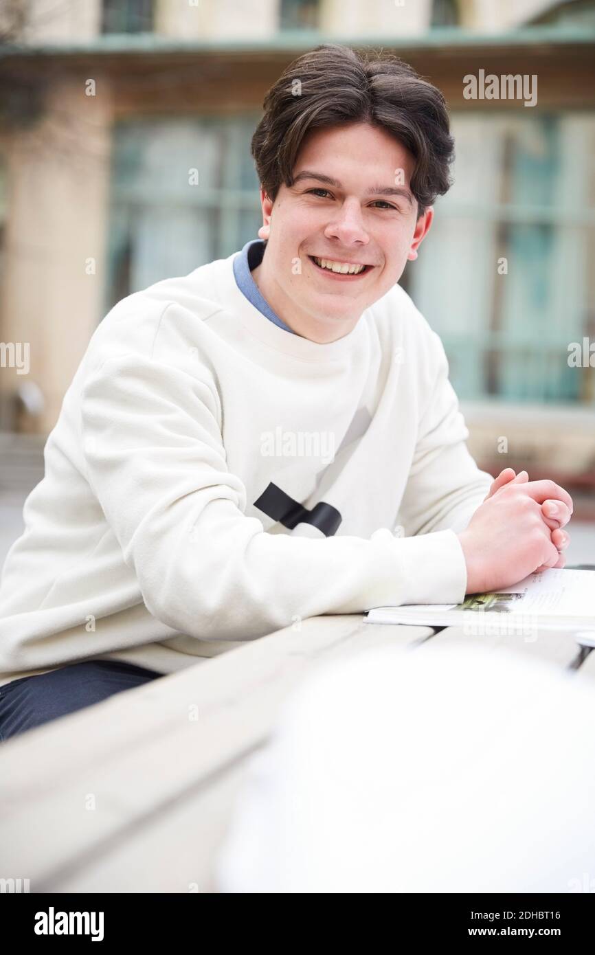 Portrait d'un adolescent confiant assis à table dans la cour d'école Banque D'Images