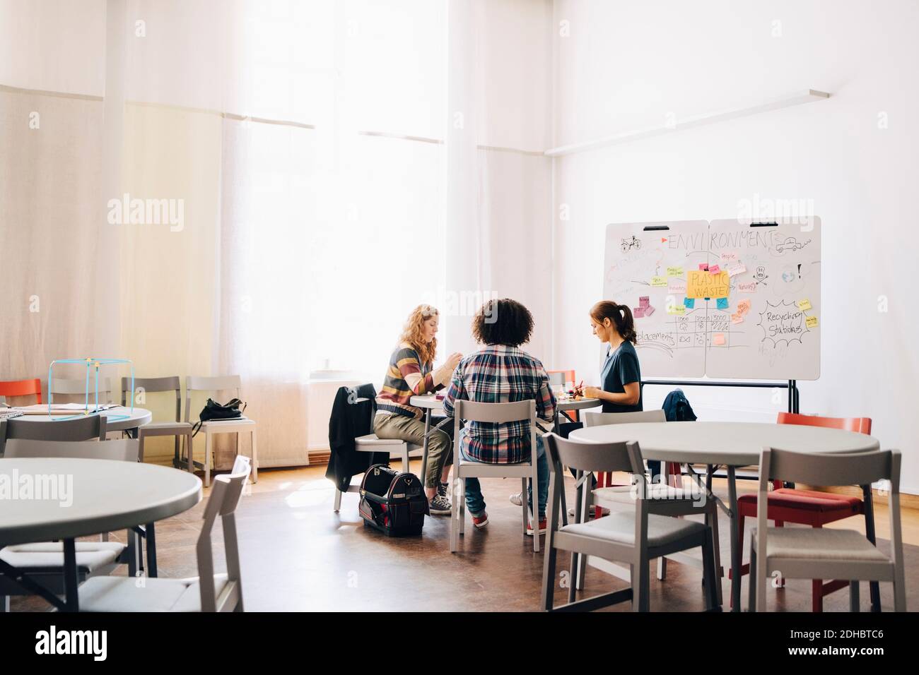 Équipe d'ingénieurs multiethniques travaillant sur table par tableau blanc dans bureau créatif Banque D'Images