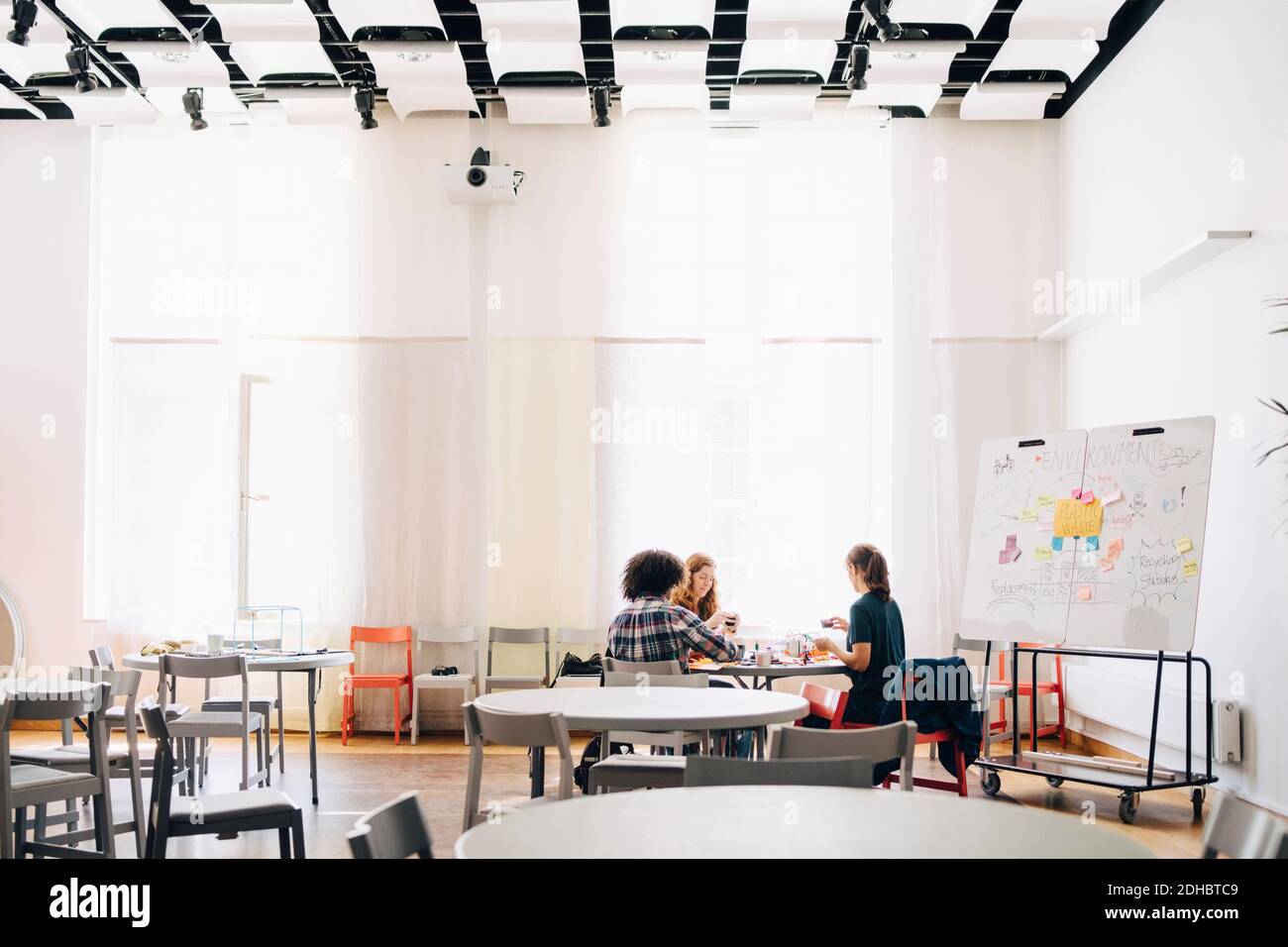 Équipe de techniciens multiethniques travaillant sur table par tableau blanc dans bureau créatif Banque D'Images