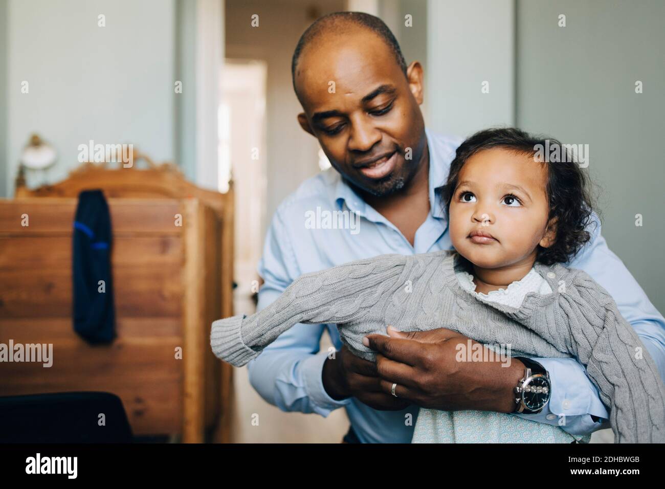 Père mature dressing fille dans la salle de séjour Banque D'Images