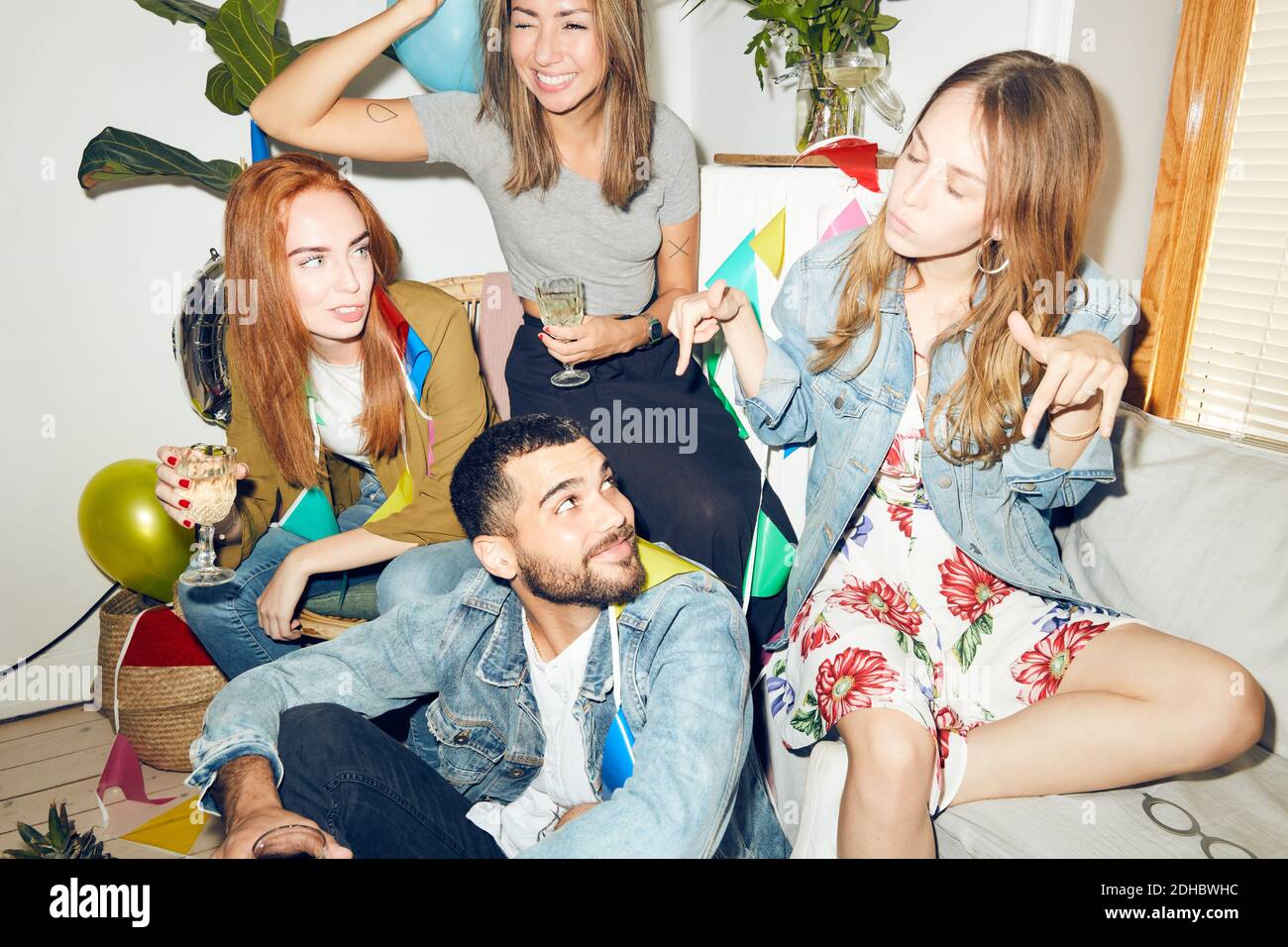 Amis regardant la femme gestante tout en appréciant la fête à l'appartement Banque D'Images