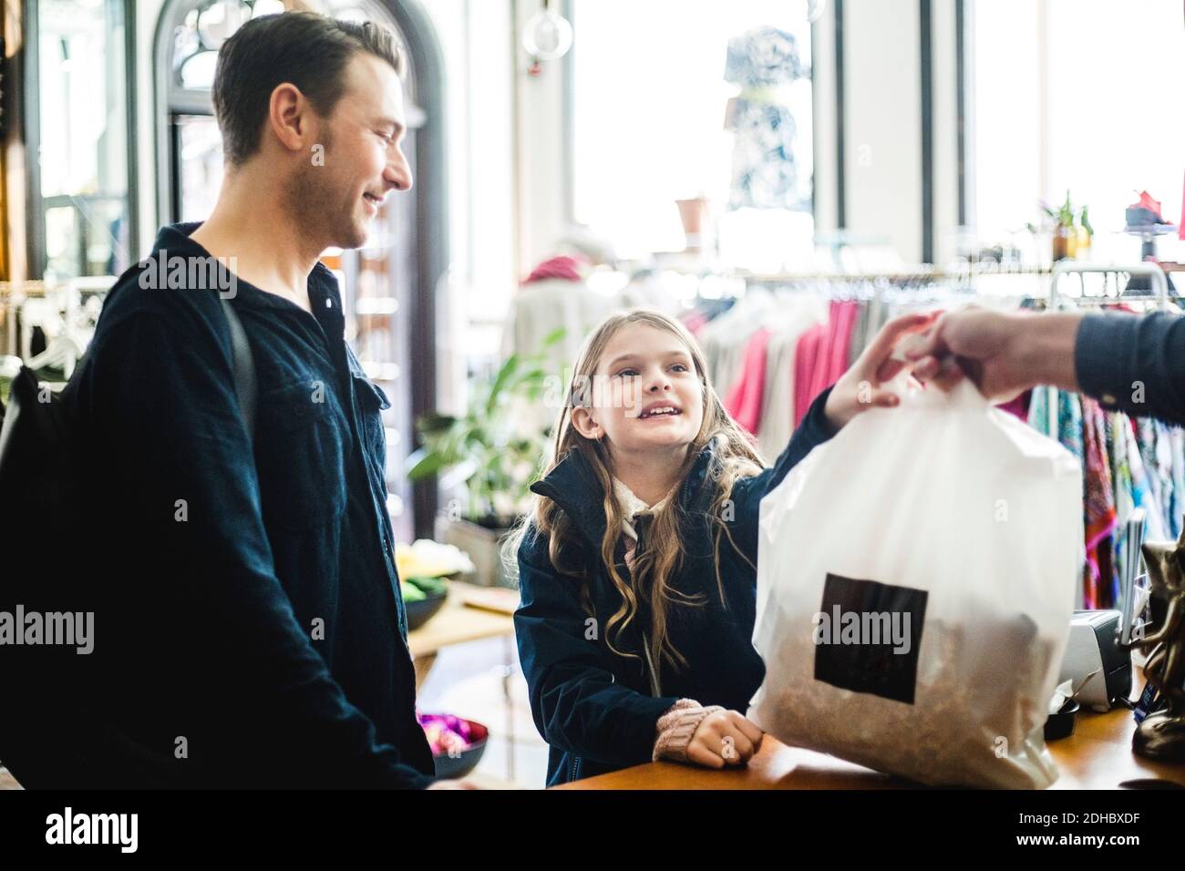 Petite fille qui reçoit un sac de shopping de la caisse par son père à comptoir de caisse Banque D'Images
