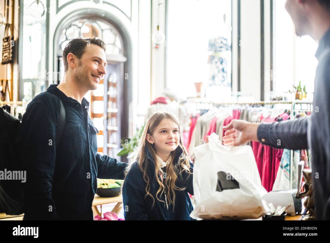 La famille reçoit le sac d'achats du vendeur au comptoir de caisse boutique Banque D'Images