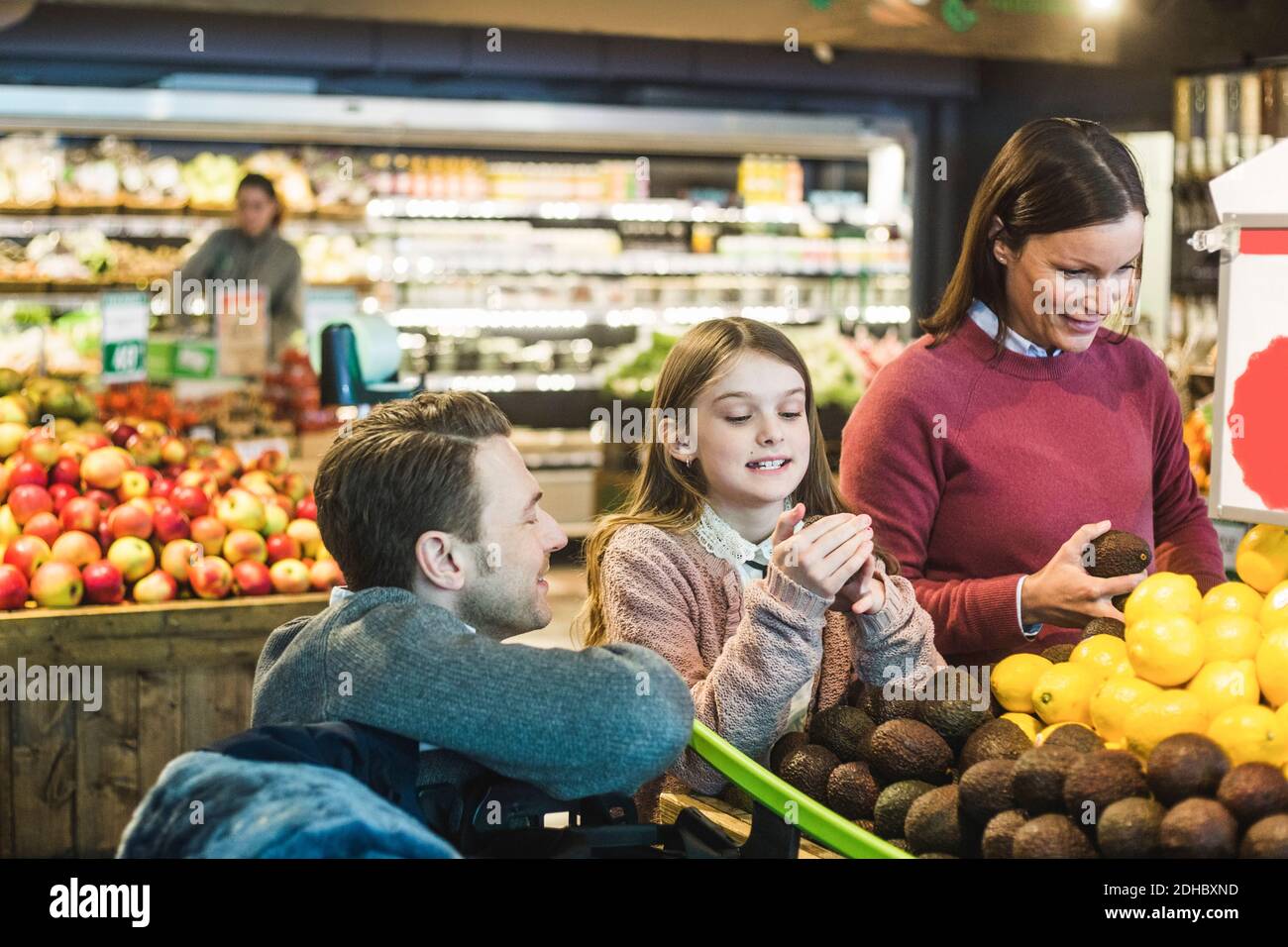 Vue latérale d'un père souriant qui regarde sa fille et sa femme shopping dans un supermarché Banque D'Images