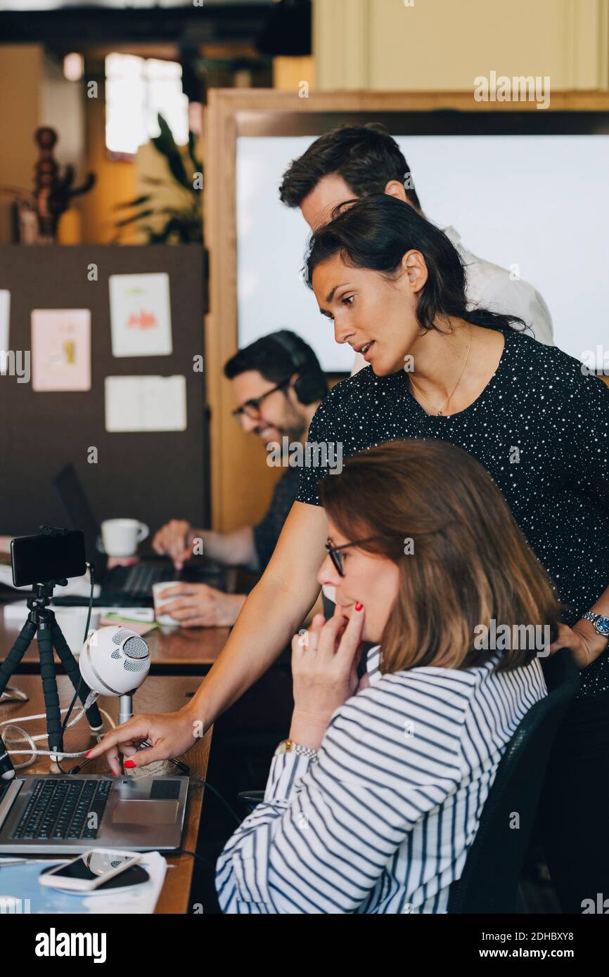 Femme d'affaires moyenne adulte discutant avec l'équipe sur un ordinateur portable au bureau Banque D'Images