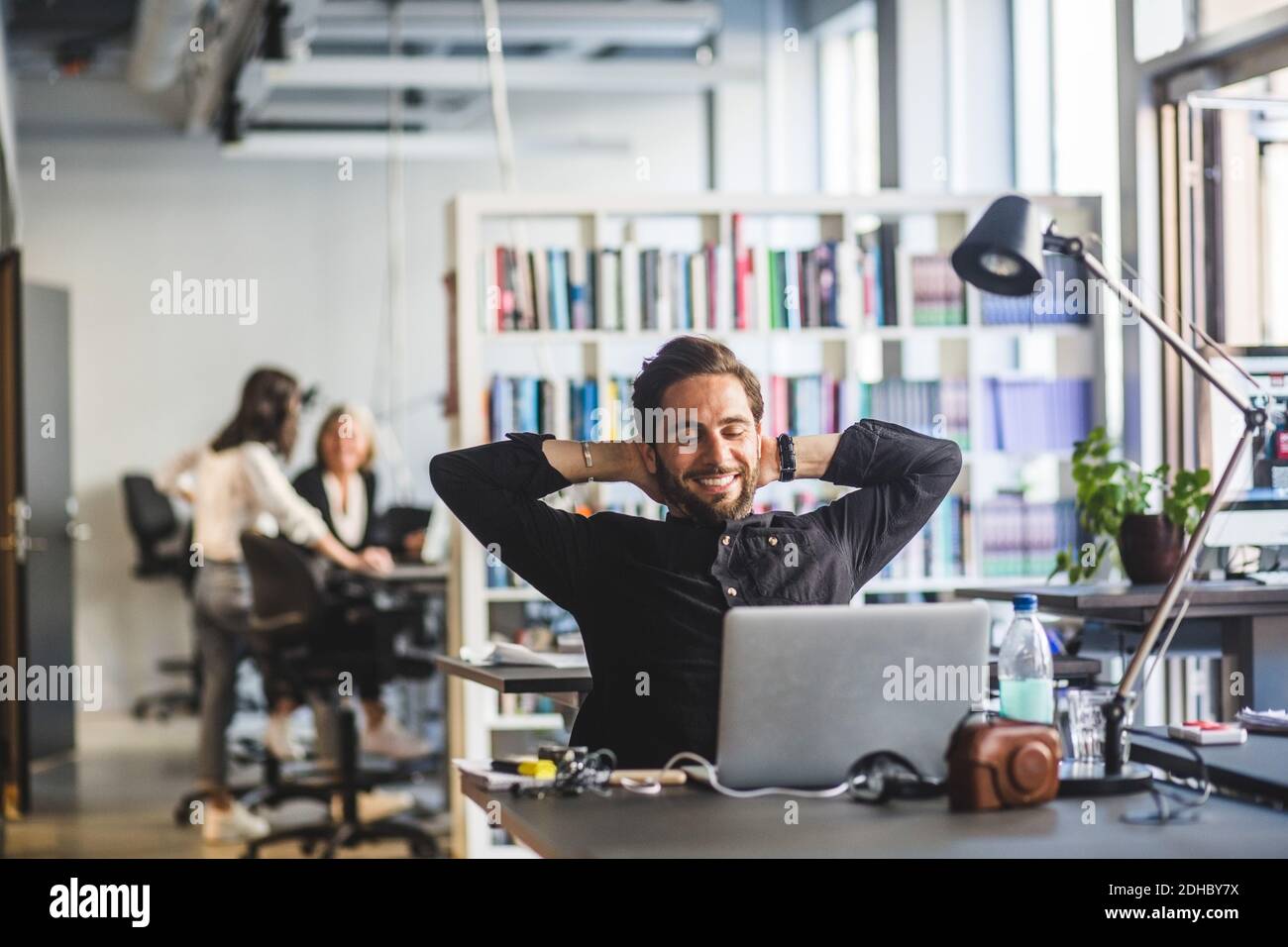 Homme d'affaires assis avec les mains derrière la tête au bureau Banque D'Images
