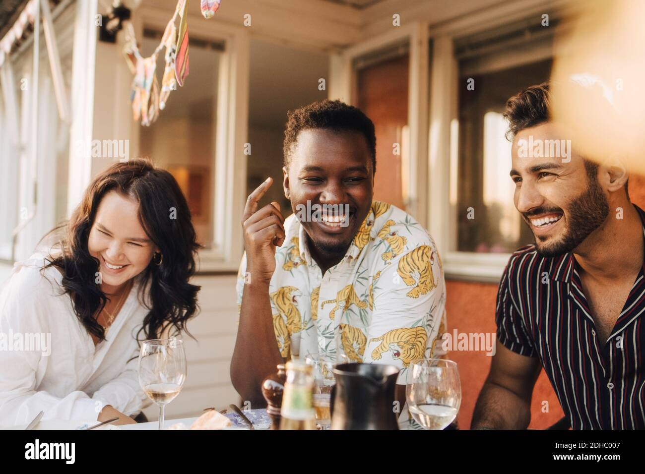 Amis joyeux s'amuser à la table à manger pendant le dîner Banque D'Images