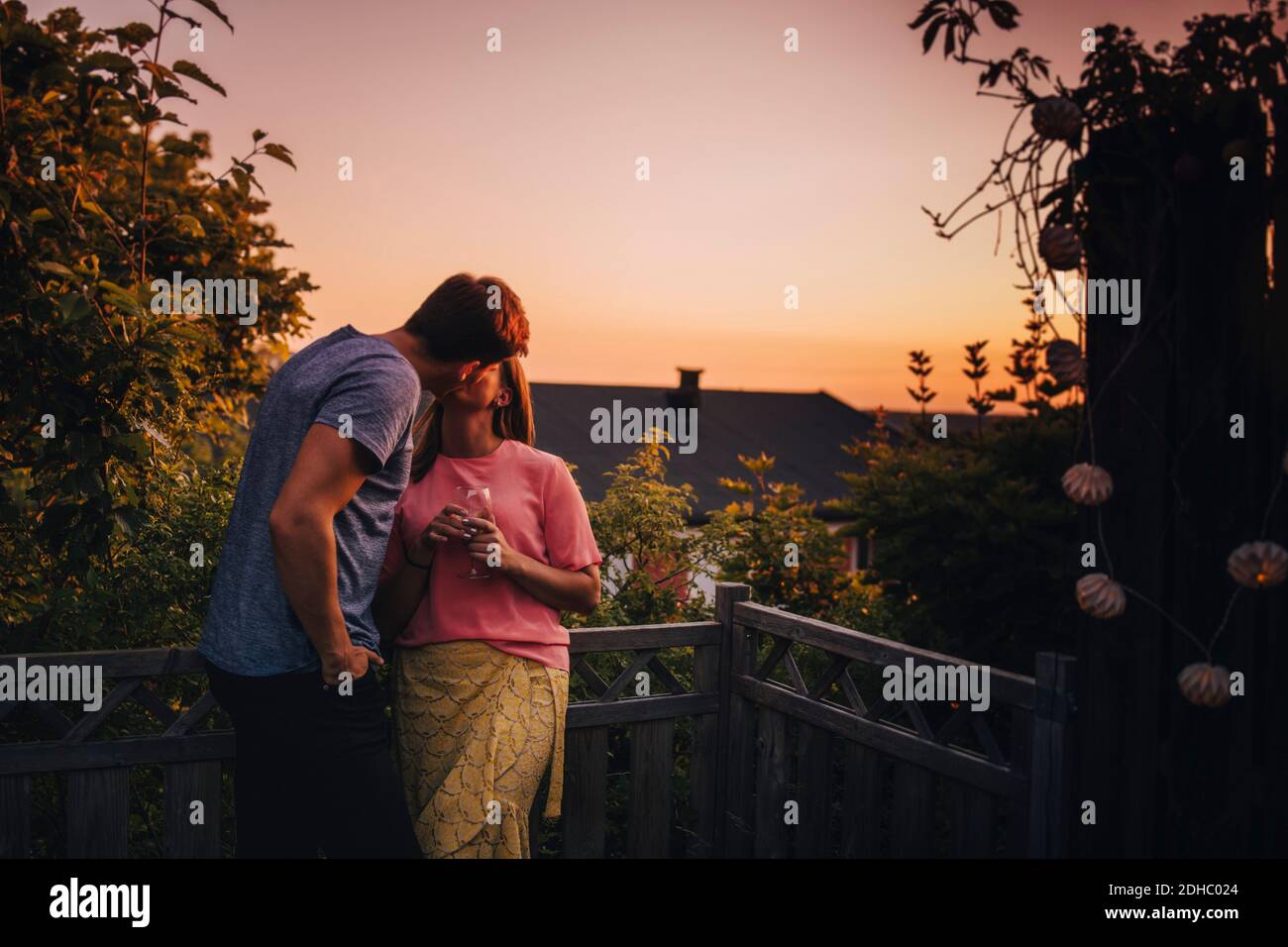 Couple embrassant en se tenant sur le balcon pendant le coucher du soleil Banque D'Images