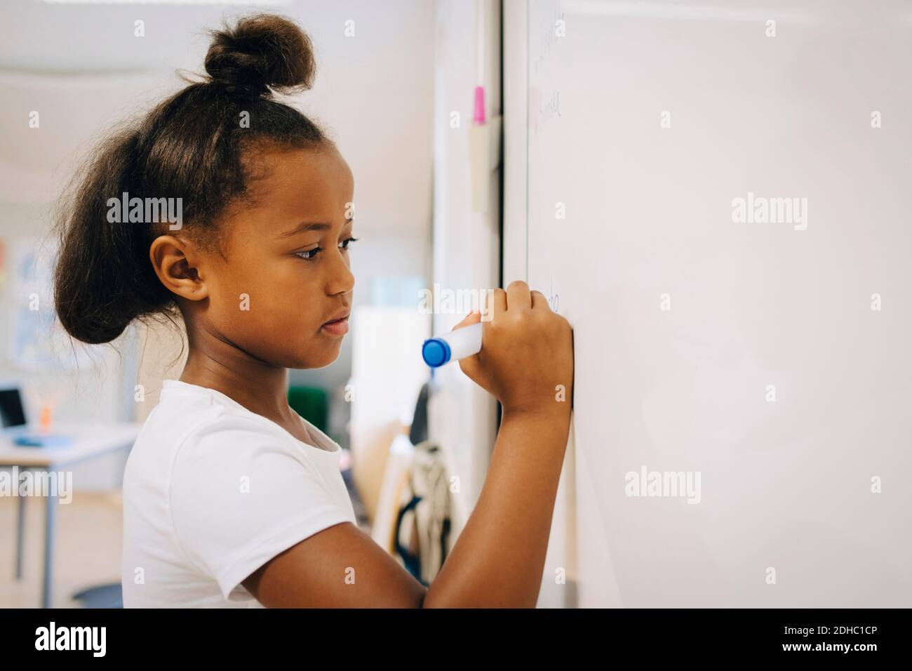 Une écolière écrivant sur un tableau blanc en classe Banque D'Images