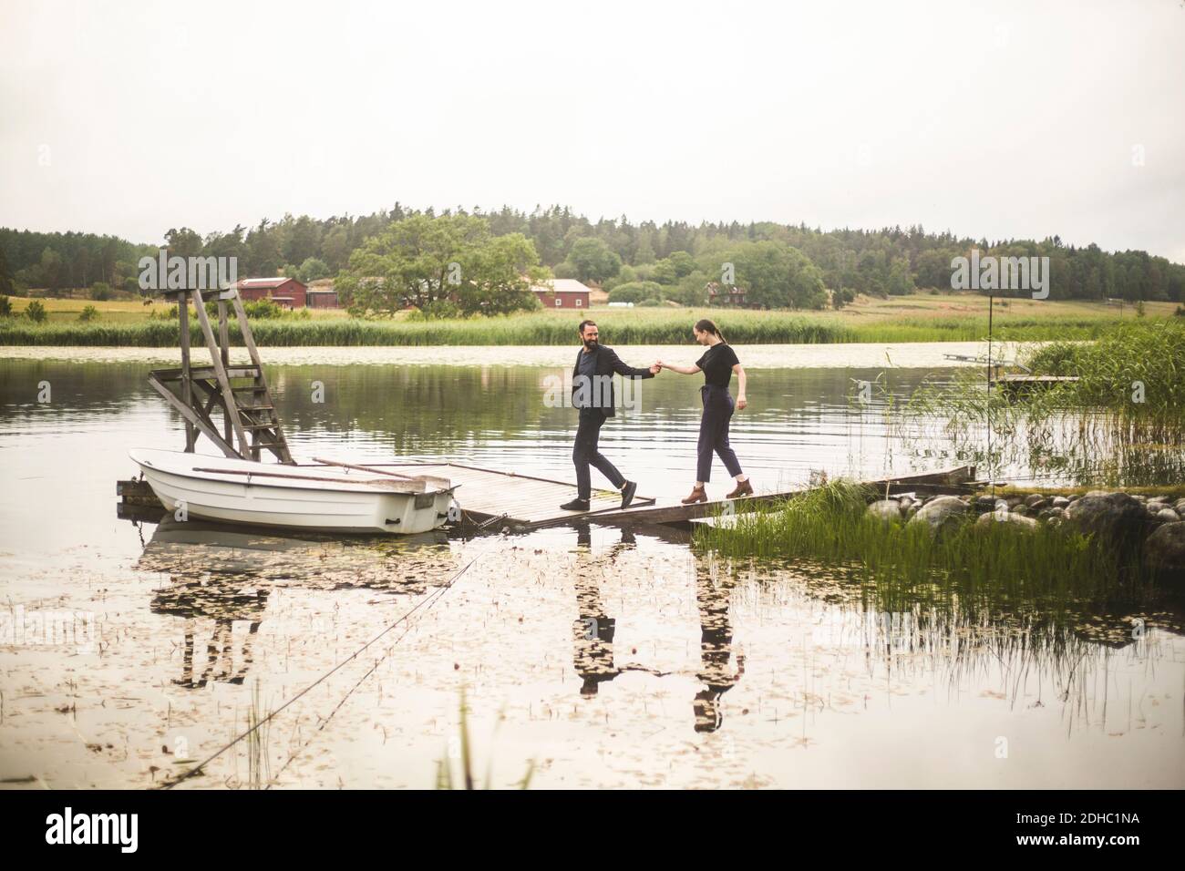 Couple tenant les mains en marchant vers la jetée au-dessus du lac pendant escapade d'un week-end Banque D'Images