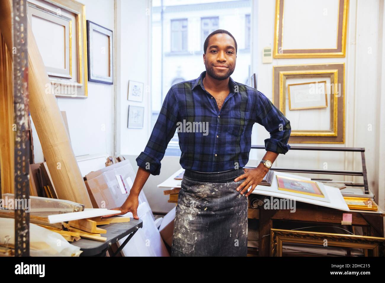 Portrait d'un jeune artiste souriant debout à la main hip à l'atelier de cadrage Banque D'Images