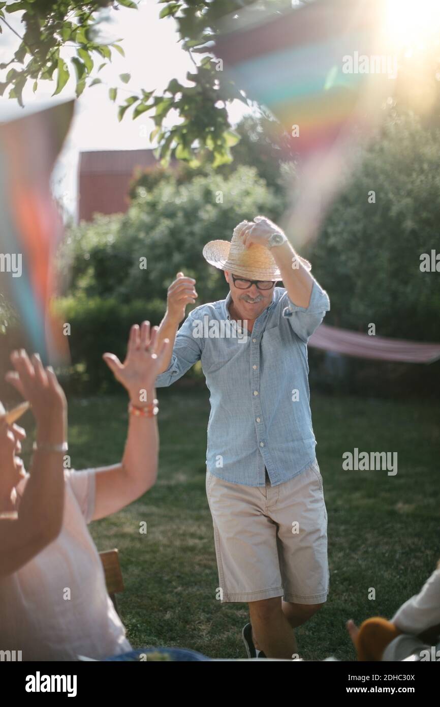 Femme âgée qui claque pendant que l'homme porte un chapeau de paille et marche dans l'arrière-cour pendant la journée ensoleillée Banque D'Images