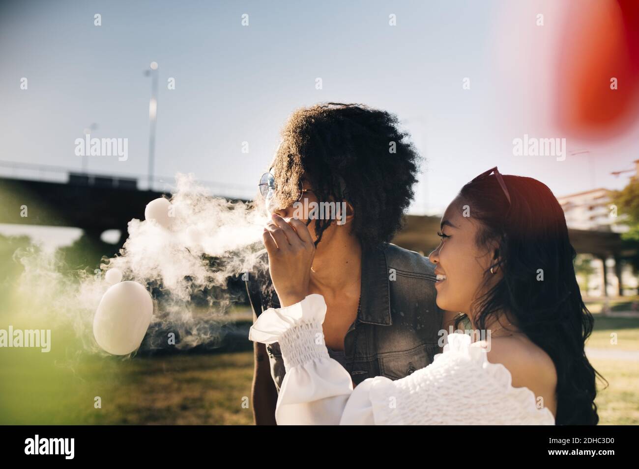 Femme joueur regardant l'homme exhalant des bulles de fumée dans la musique festival Banque D'Images